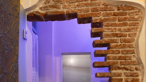A hallway with a brick wall archway leading to a door.