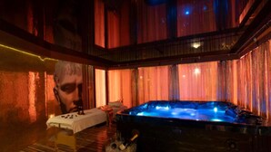 A hot tub in a dimly lit room with a table and a chair.