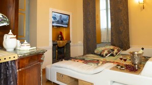 A room with a bed, a television, a fireplace, and a wooden cabinet.