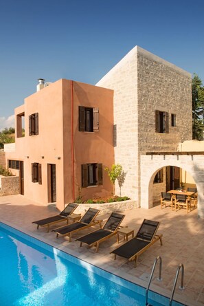 A modern building with a pool, lounge chairs, and outdoor seating.