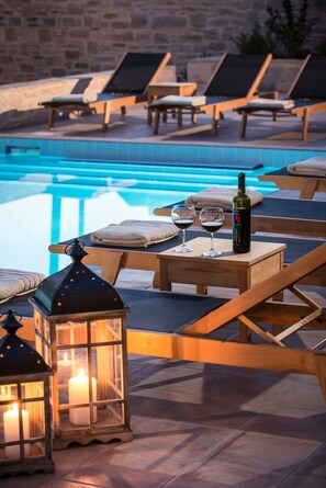 A poolside area with lounge chairs, a table with a bottle and glasses, and lanterns. - Phaistos Villas - Villa Kastalia Poolside Retreat (Faistos)