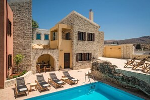 A stone building with a pool, outdoor seating, and a view of the landscape. - Phaistos Villas - Villa Kastalia Poolside Retreat (Faistos)