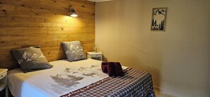 A bedroom with a wooden headboard, two pillows, a bedside table, a lamp, and a framed picture on the wall. - House on the river (La Bresse)