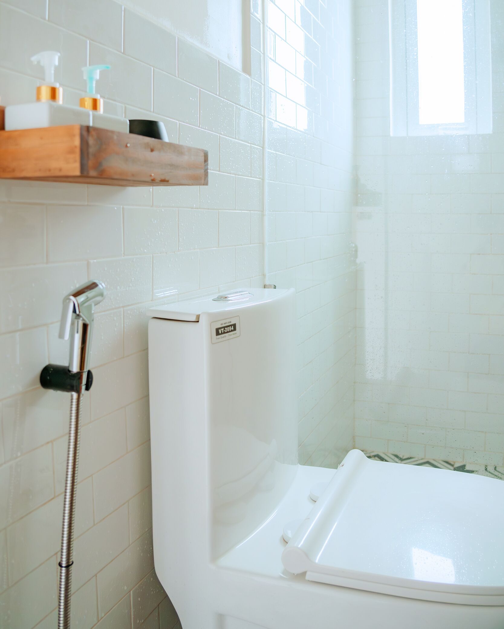 Un bagno con il water bianco, una doccia e una finestra.