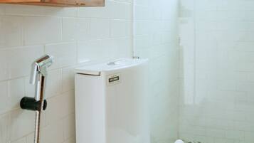Un bagno con il water bianco, una doccia e una finestra.