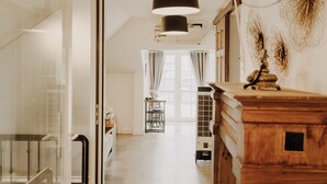 Um corredor com um aparador de madeira, um radiador e uma janela com cortinas.