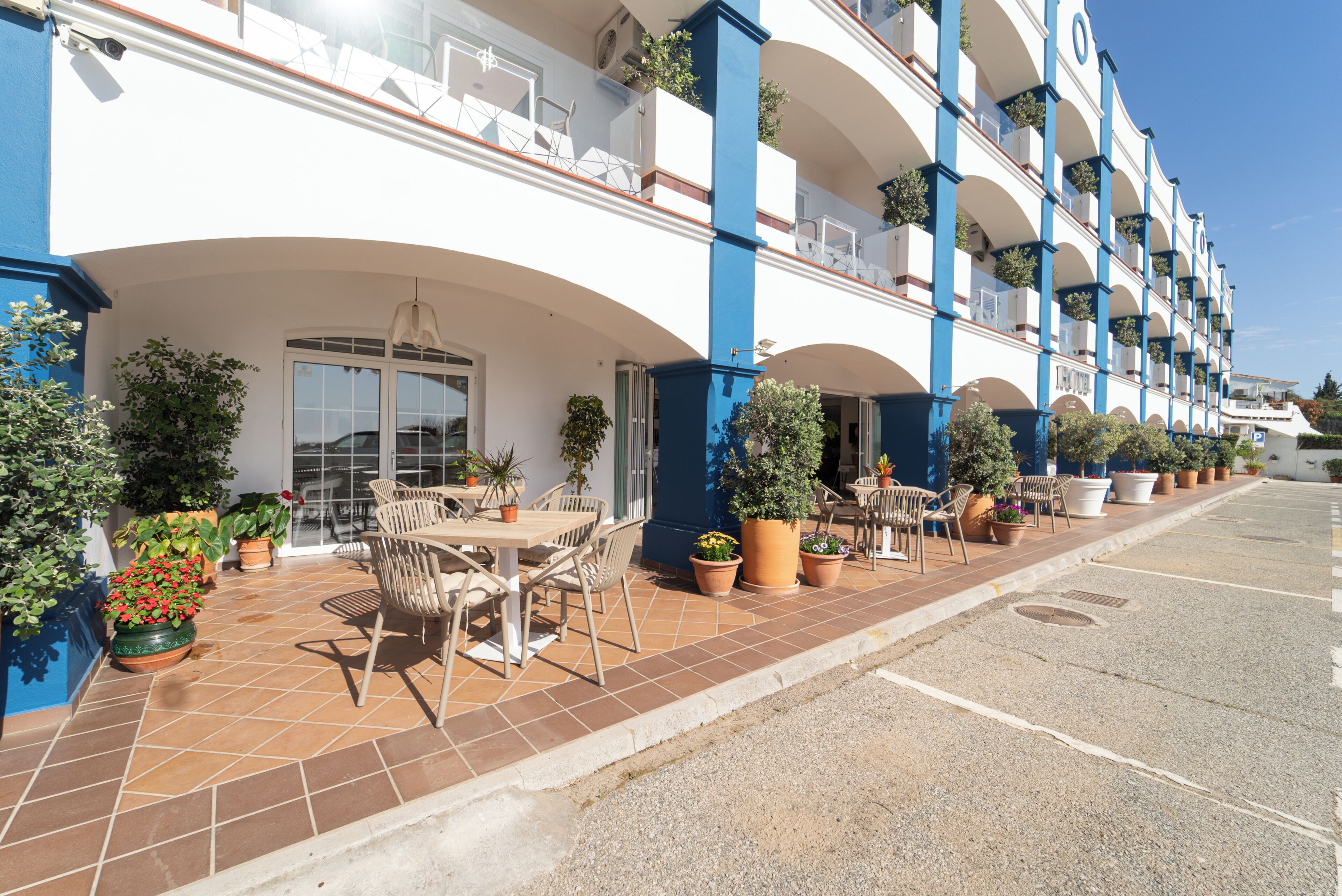 Ein Hotel mit Außenbereich, Pflanzgefäßen und blauem Himmel.