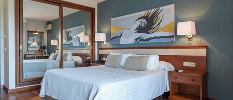Une chambre d’hôtel avec un grand lit, une table de chevet, un miroir et un tableau au mur.
