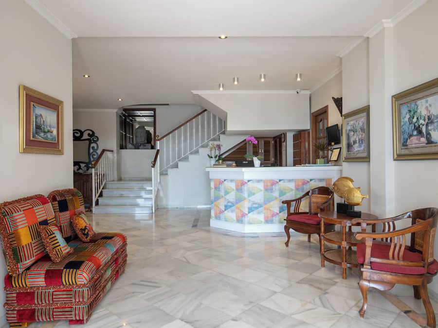 Ein geräumiger Wohnbereich mit einer Couch, Sesseln, einem Couchtisch und einer Treppe, die zu einer weiteren Ebene führt.