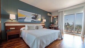A hotel room with a large bed, two bedside tables, a nightstand, a painting on the wall, and a balcony with a view. - Hotel Piedra Paloma by Croma (Estepona)