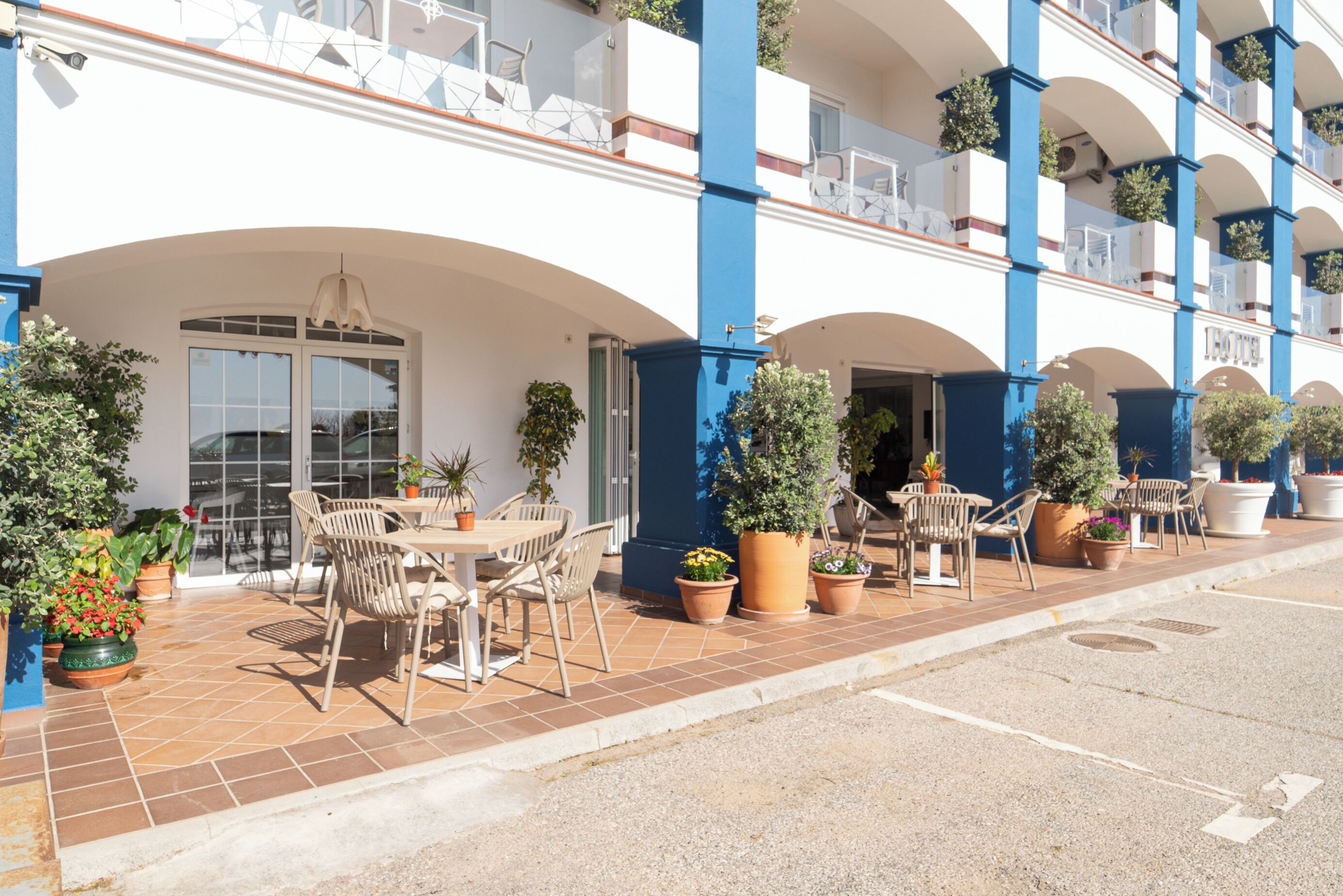 A hotel with outdoor seating and potted plants.