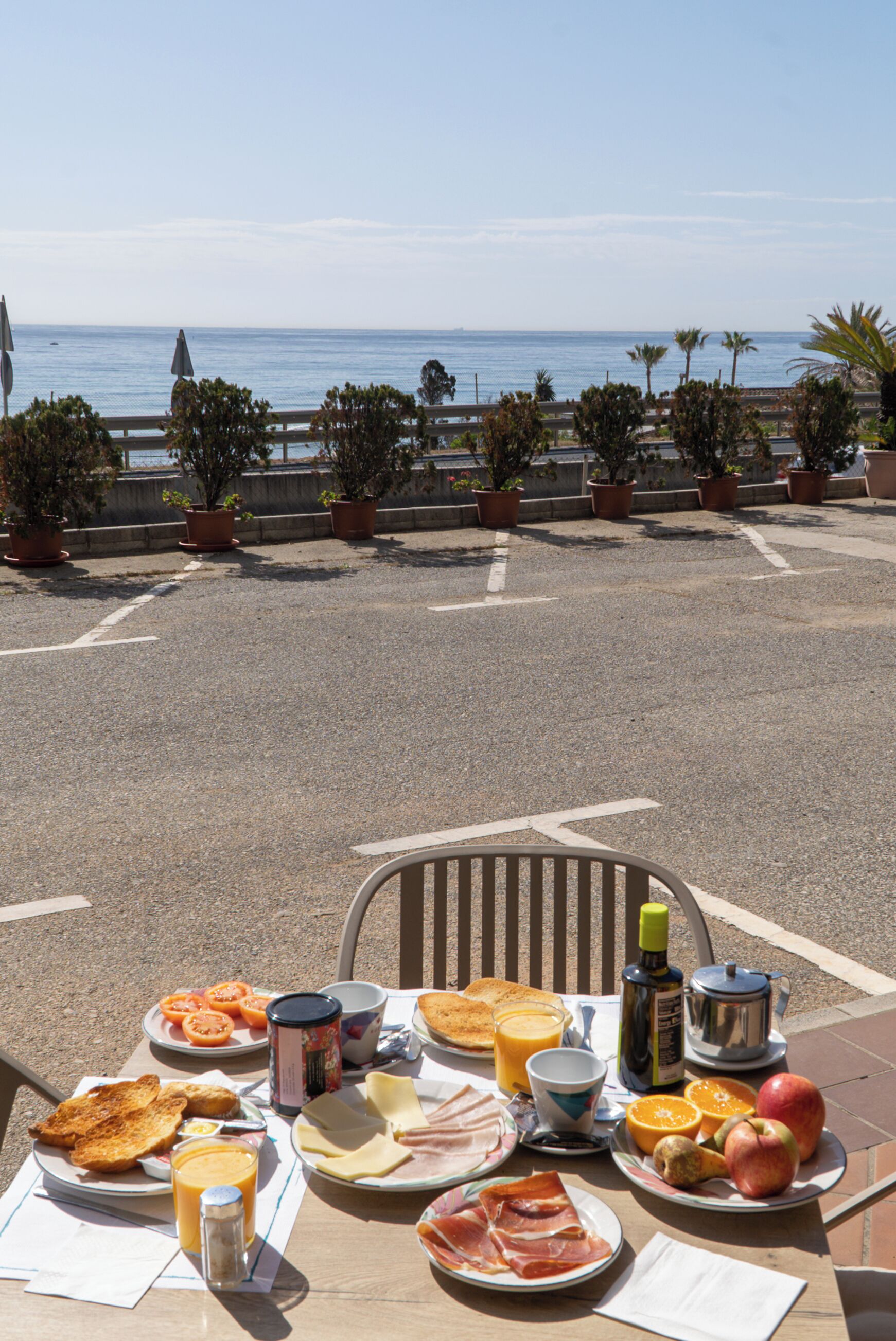 A breakfast table with a variety of food items and a view of the sea.