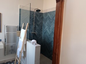 Bathroom features a herringbone-patterned tile design, glass-enclosed shower, and a towel rack with a rolled towel.