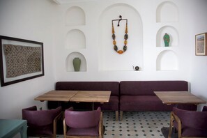 Cozy retreat with a wooden table, matching bench, and two chairs, set against a backdrop of white walls and decorative arches.