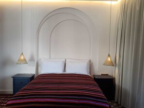 Classic hotel room with a large bed, two nightstands, and an arched headboard.