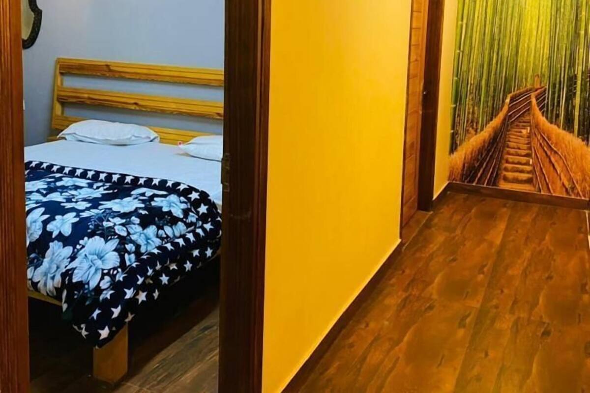 A room with a bed, wooden ceiling, and a staircase with a green wall.