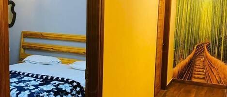 A room with a bed, wooden ceiling, and a staircase with a green wall.