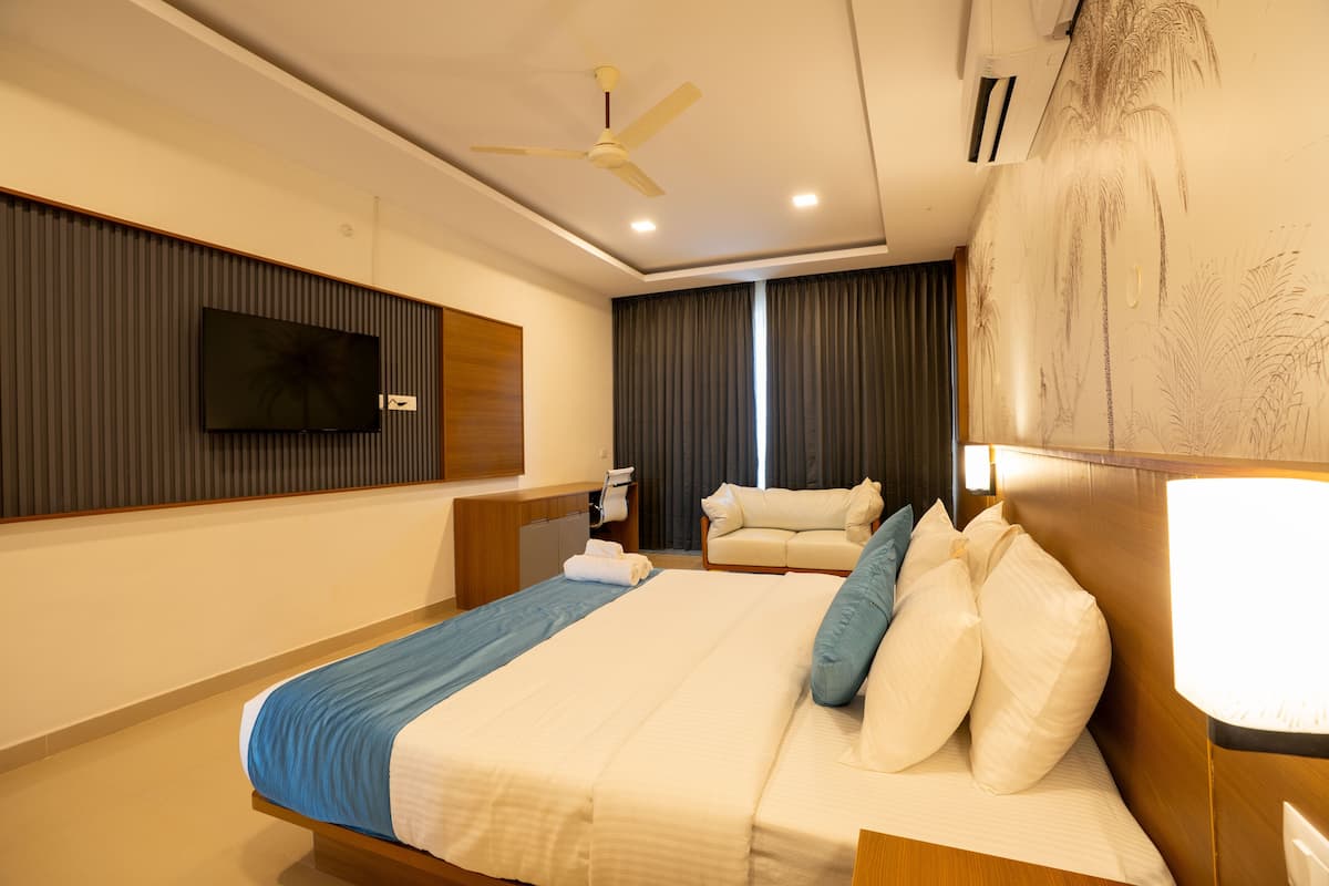A hotel room with a bed, a desk, a chair, a TV, and a ceiling fan.