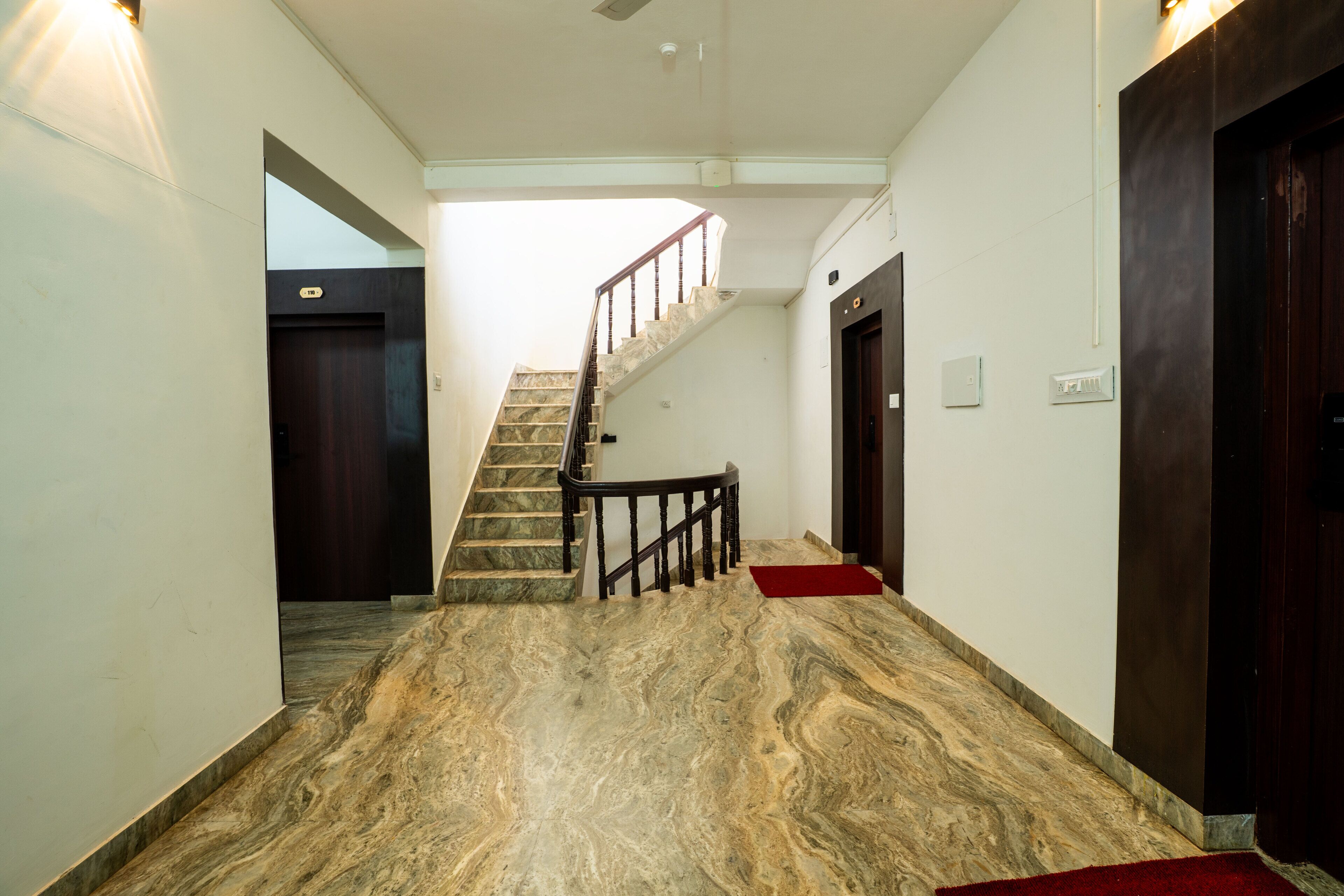 A hallway with marble flooring, a staircase, and wooden doors.