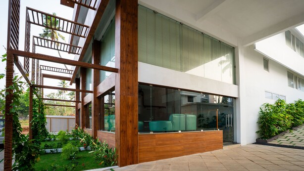 Un edificio moderno con ampie finestre, un balcone in legno e un giardino curato.