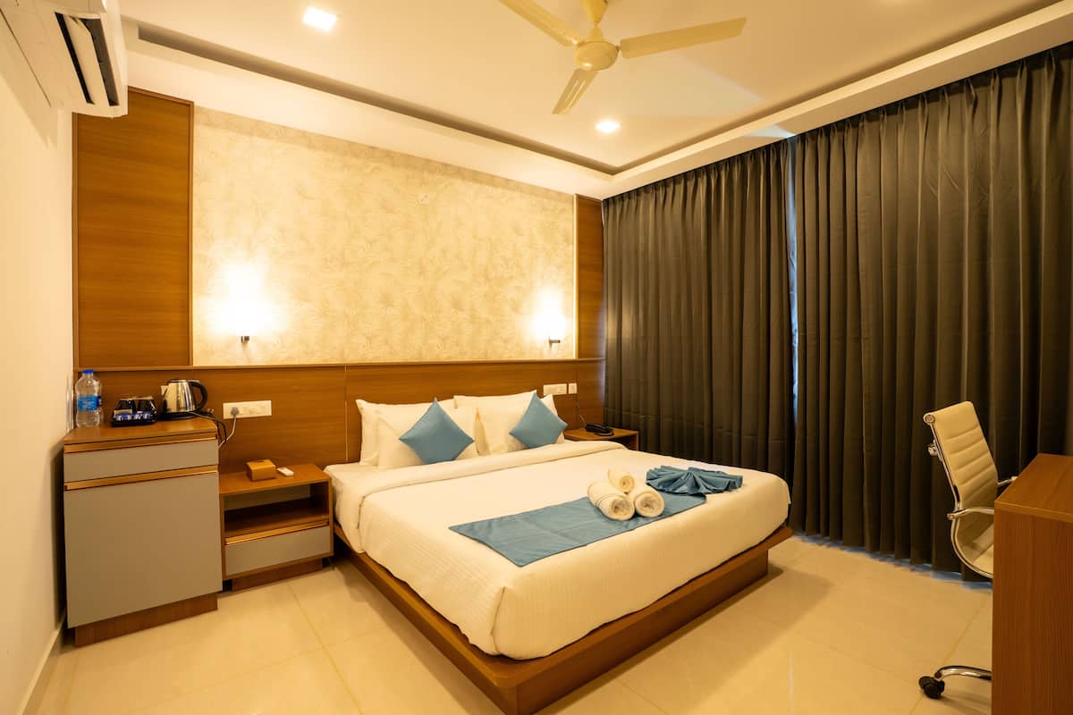 A hotel room with a bed, bedside table, lamp, and a desk with a chair.