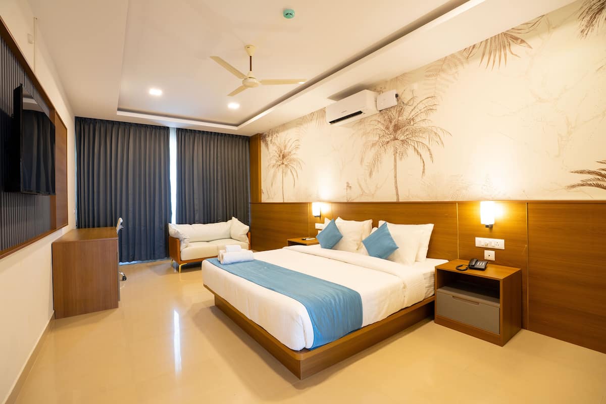 A modern hotel room with a large bed, a wooden headboard, a nightstand with a phone, and a ceiling fan.