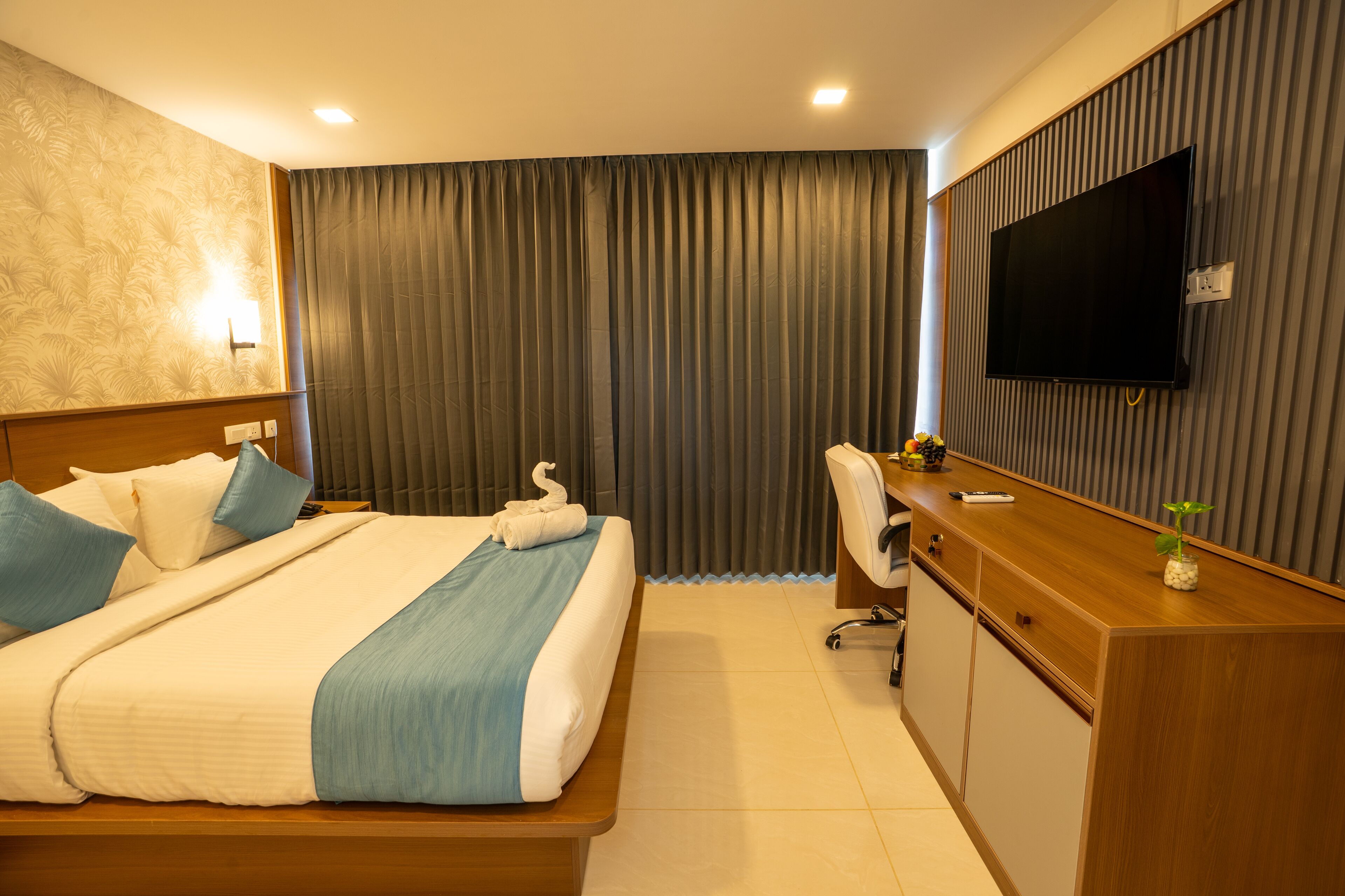 A hotel room with a bed, a desk, a television, and a curtain.