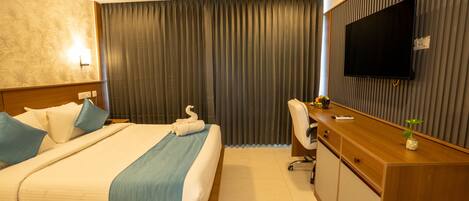 A hotel room with a bed, a desk, a television, and a curtain.