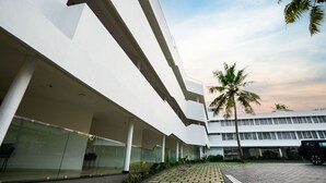 Un edificio moderno con facciata in vetro, un vialetto lastricato e un veicolo parcheggiato.
