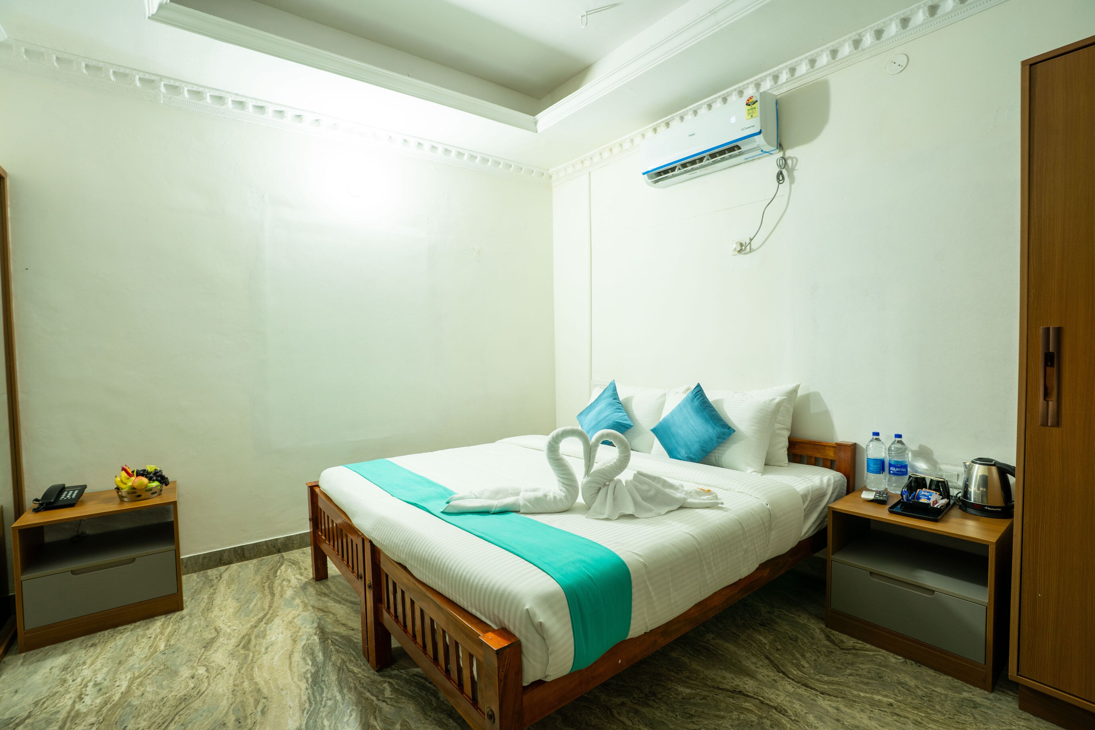 A hotel room with a bed, a nightstand, a wardrobe, and a wall-mounted air conditioner.