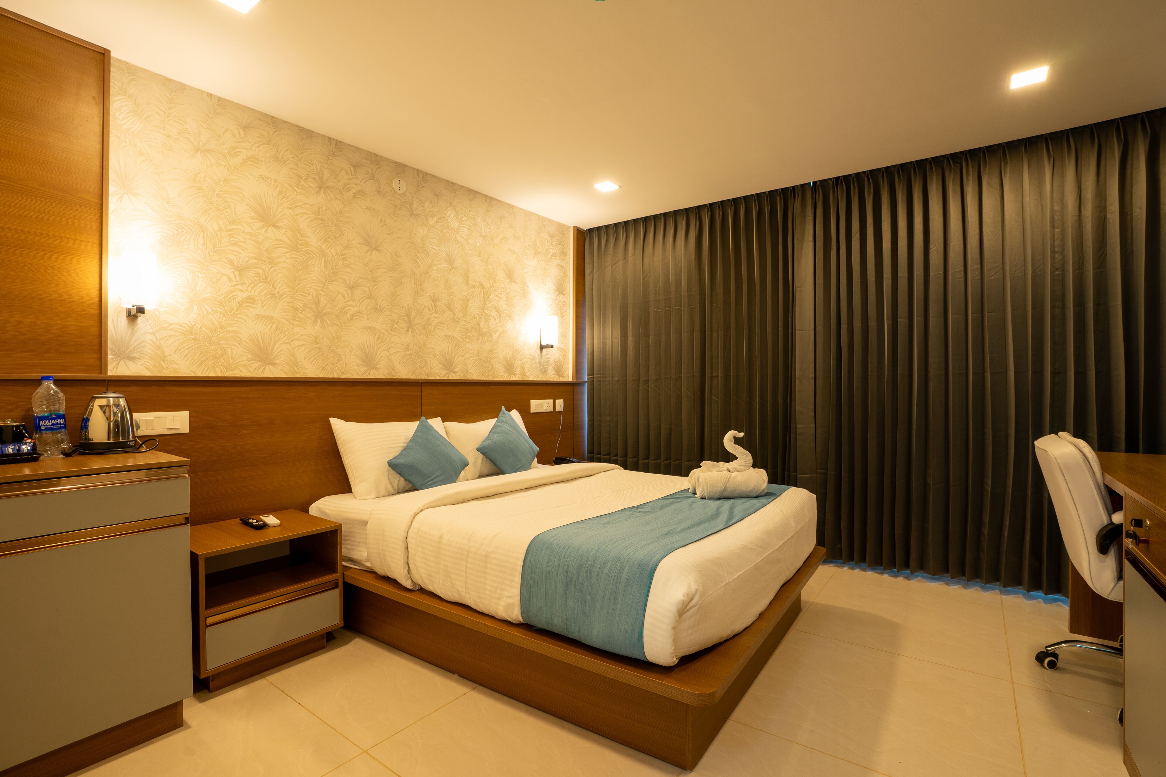 Una habitación de hotel moderna con una cama grande, cabecera de madera y un escritorio con silla.
