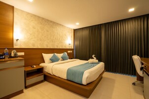 Una habitación de hotel moderna con una cama grande, cabecera de madera y un escritorio con silla.