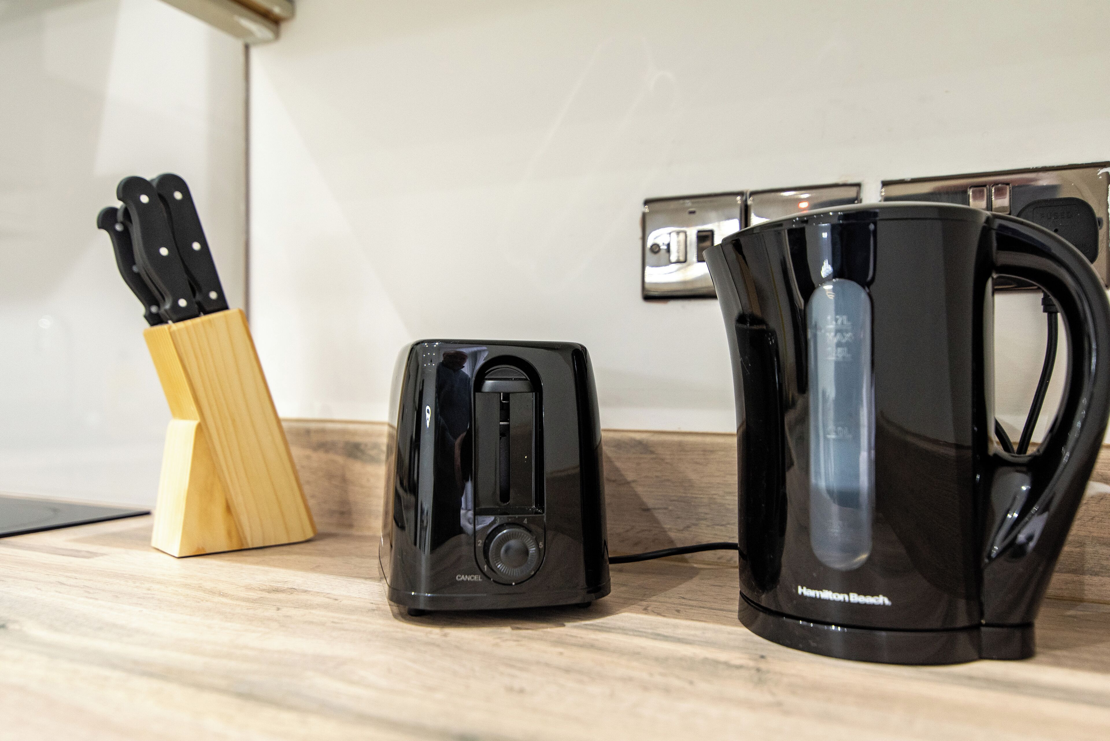 A kitchen counter with a toaster, a coffee maker, and a knife block.