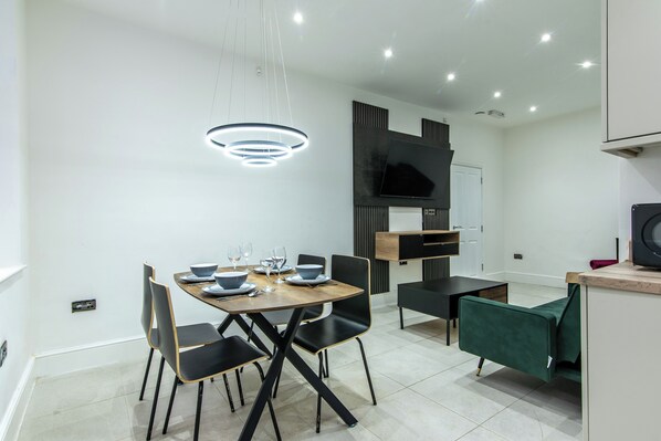 A modern dining area with a round table, black chairs, and a contemporary light fixture.