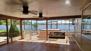 A sunroom with a view of a lake, a wooden bench, and a ceiling fan. - Spacious 3-bedroom house with HOT TUB and MOVIE THEATRE 8 minutes from RACEWAY (Sebring)