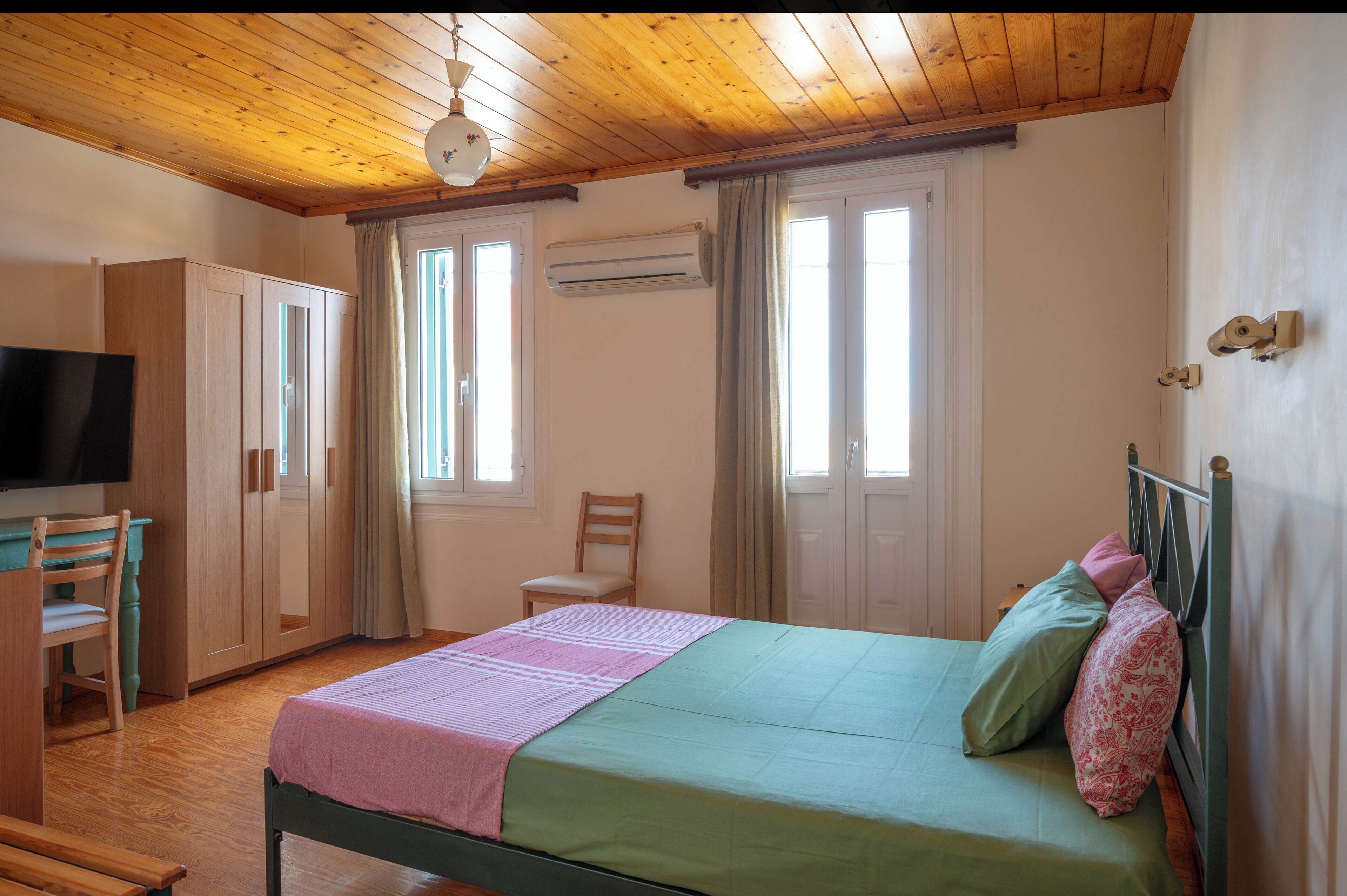 Un dormitorio con cama, televisión, armario y silla.