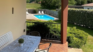 Un espacio exterior cubierto con piscina, una mesa y sillas, y vistas del paisaje circundante.
