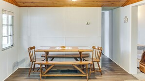 En matplats med ett träbord och stolar, en takfläkt och utsikt in i ett annat rum.