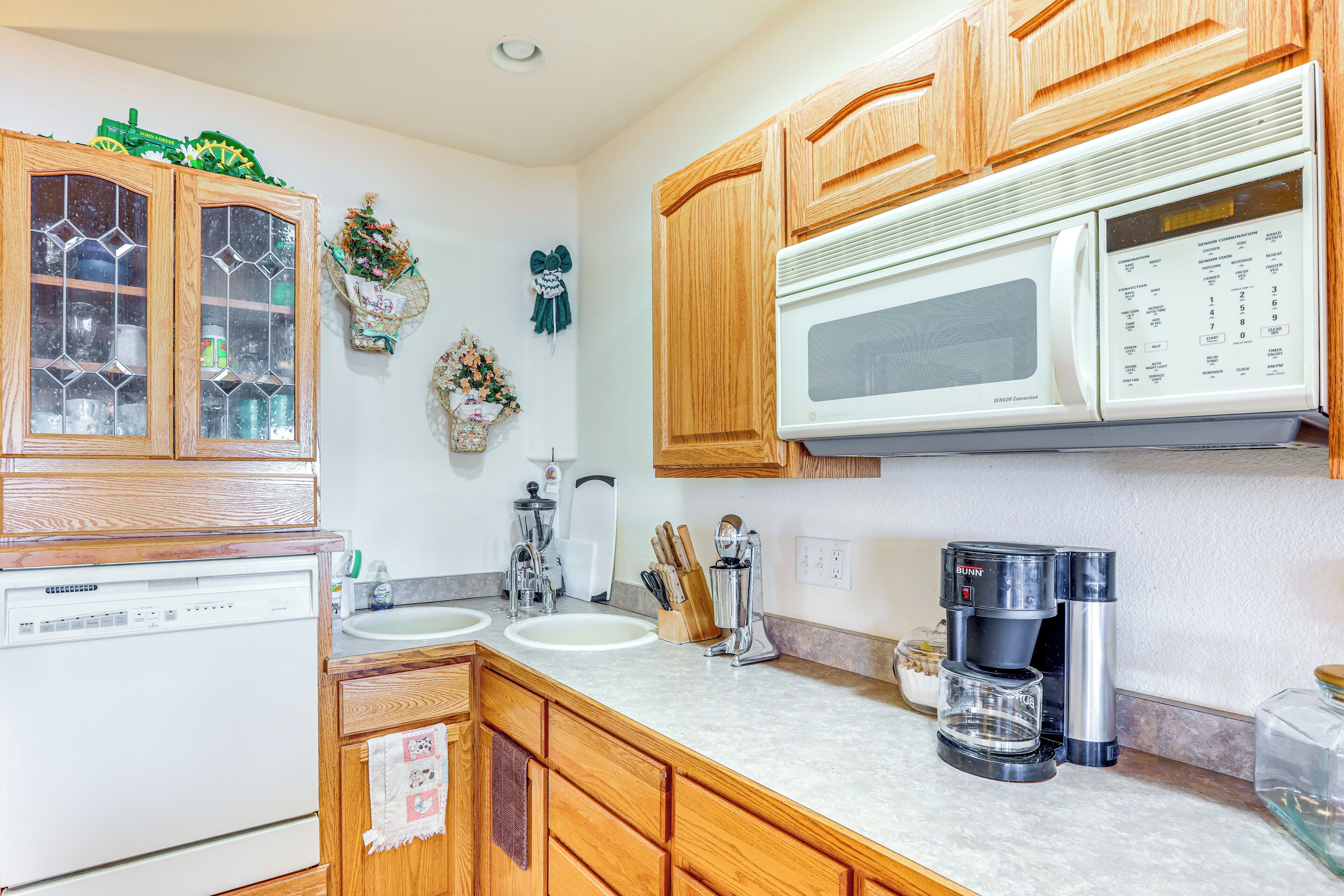 A kitchen with wooden cabinets, a microwave, a coffee maker, and a dishwasher.