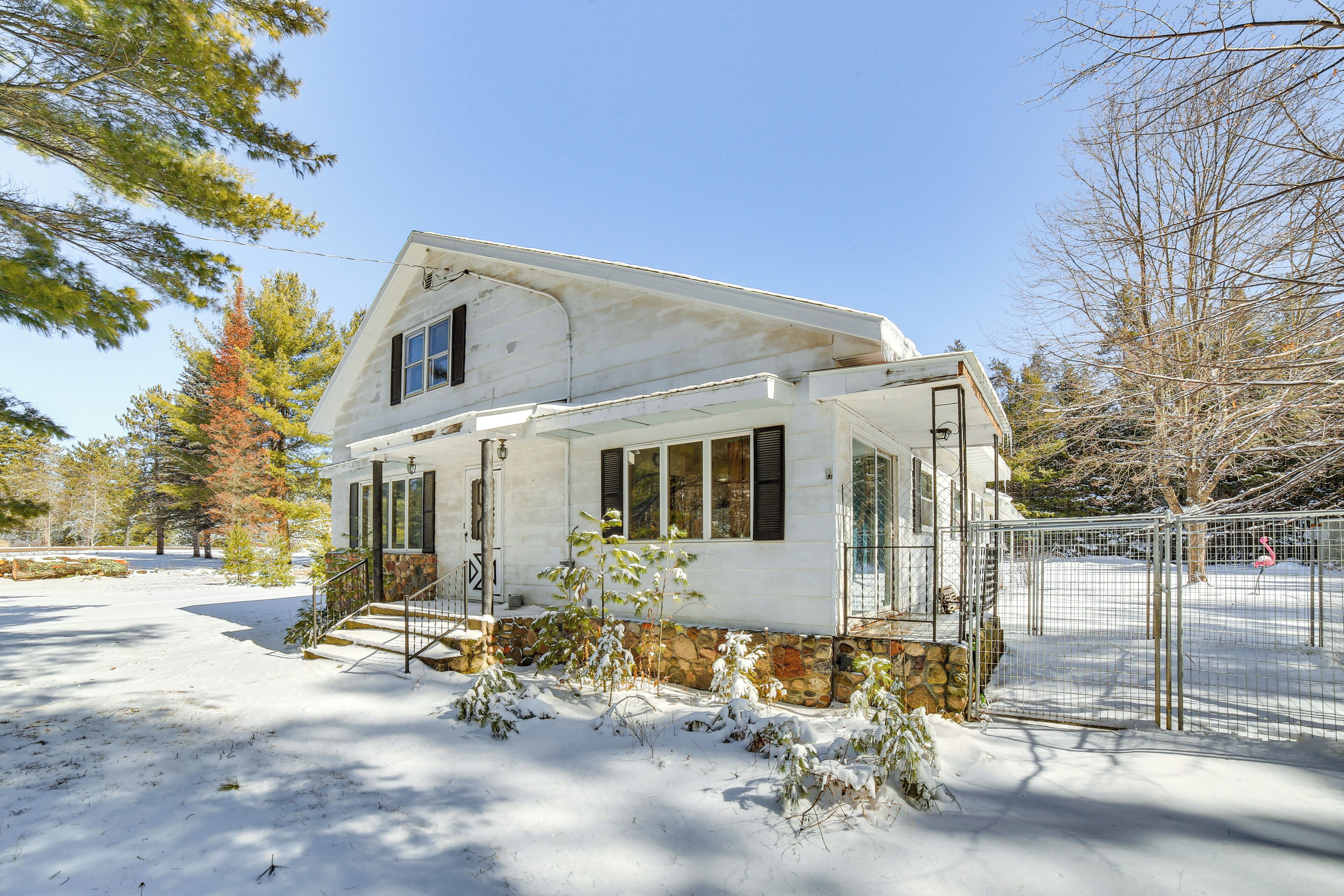 A two-story house with a stone foundation, a covered porch, and a fenced yard.