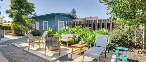 A patio area with outdoor furniture, a small shed, and a wooden fence.