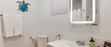 A bathroom with a toilet, sink, and mirror.