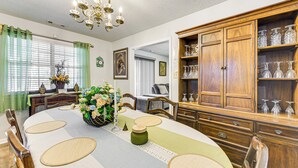 Un coin repas agrémenté d’un grand buffet en bois, d’un lustre et d’une table dressée pour six personnes.