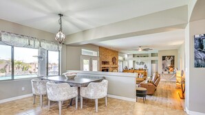 A spacious living area with a large dining table, comfortable seating, a fireplace, and a view of the outdoors. - Luxe Mtn-view Mansion w/ Hot Tub in Phoenix! (Phoenix)