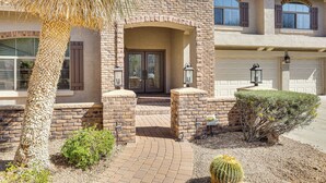 A two-story house with a brick facade, a front porch, and a garage. - Luxe Mtn-view Mansion w/ Hot Tub in Phoenix! (Phoenix)