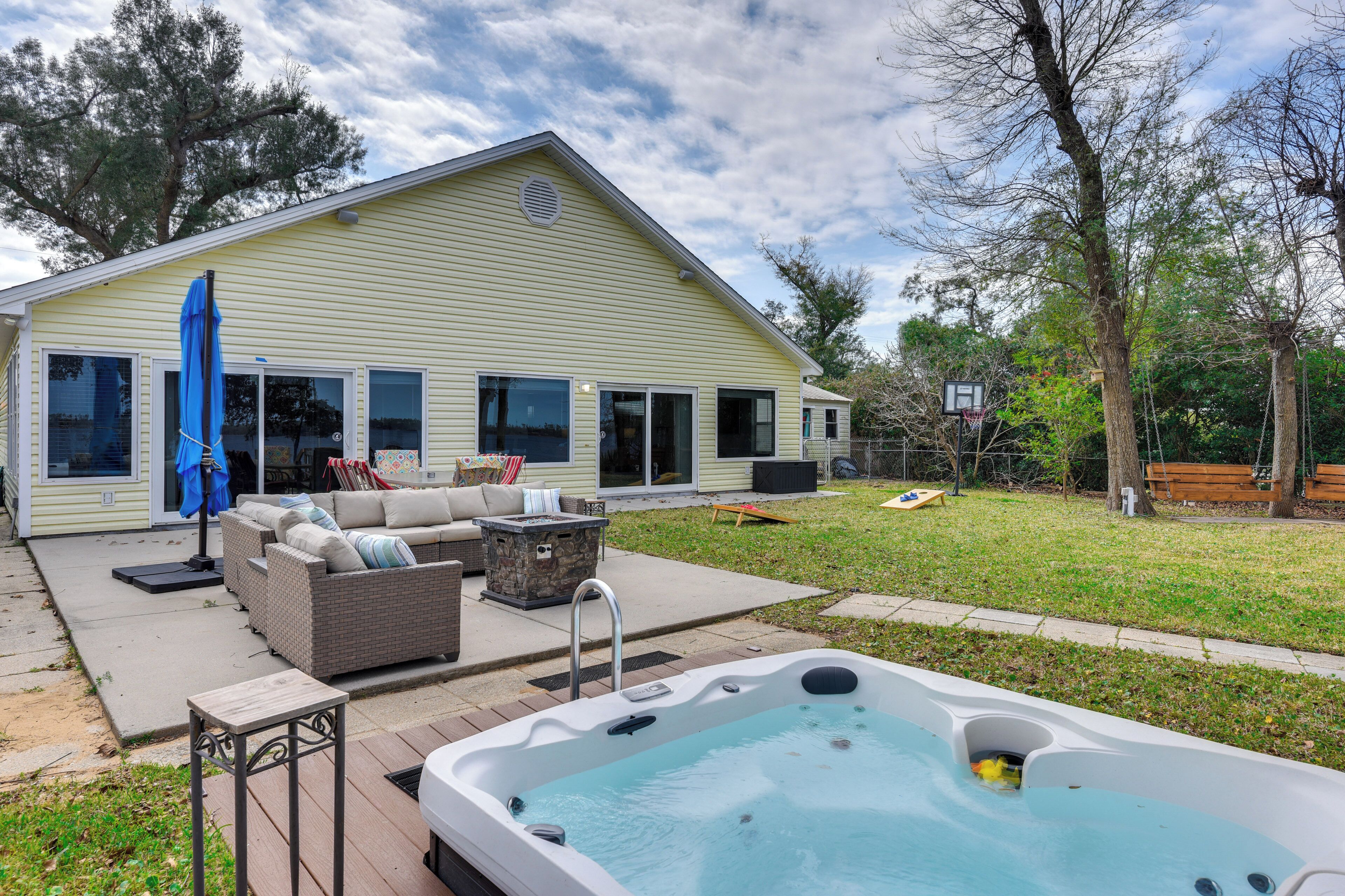 A backyard with a hot tub, outdoor furniture, and a house.
