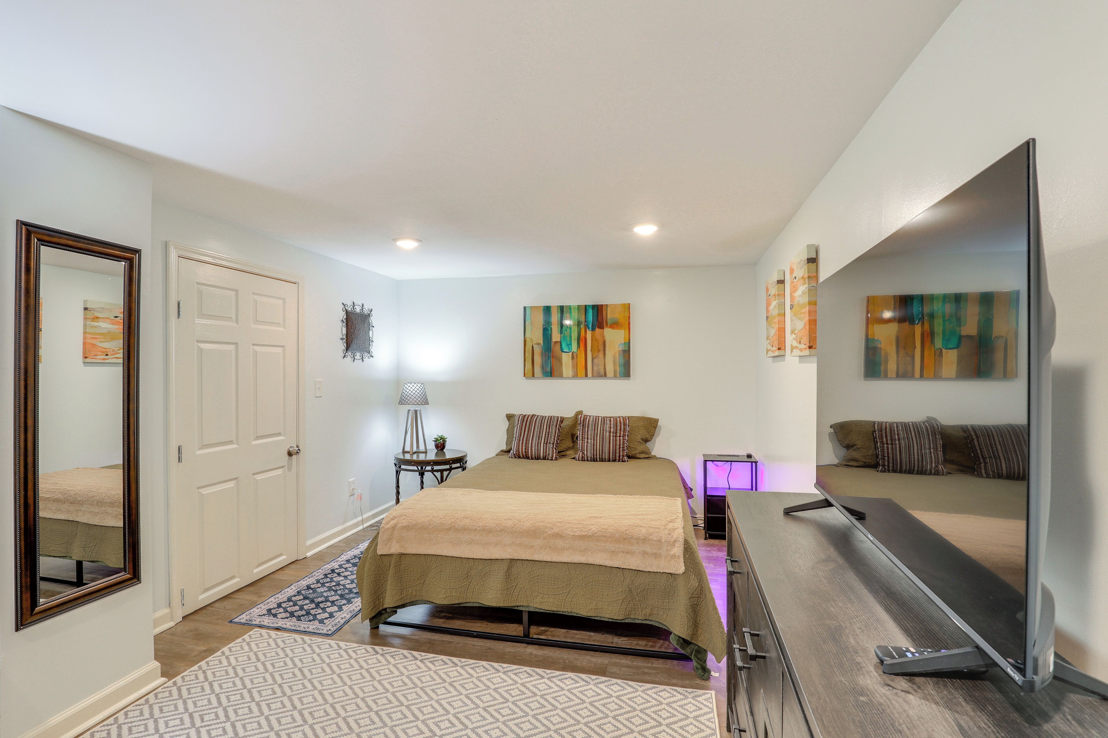 A bedroom with a bed, a TV, and artwork on the walls.