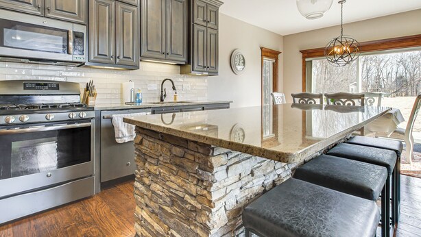 A kitchen with granite countertops, a stone island, and a large window. - 8 Mi to Lambeau Field: Family Home in De Pere! (De Pere)