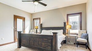 A bedroom with a dark wooden bed, a window with a view, a chair, and a desk with a lamp. - 8 Mi to Lambeau Field: Family Home in De Pere! (De Pere)