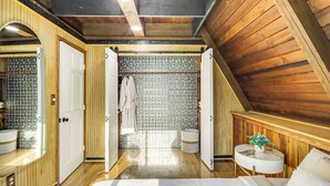 Een houten interieur met een badkamer, inclusief een betegelde muur, een rond wastafel en een spiegel.